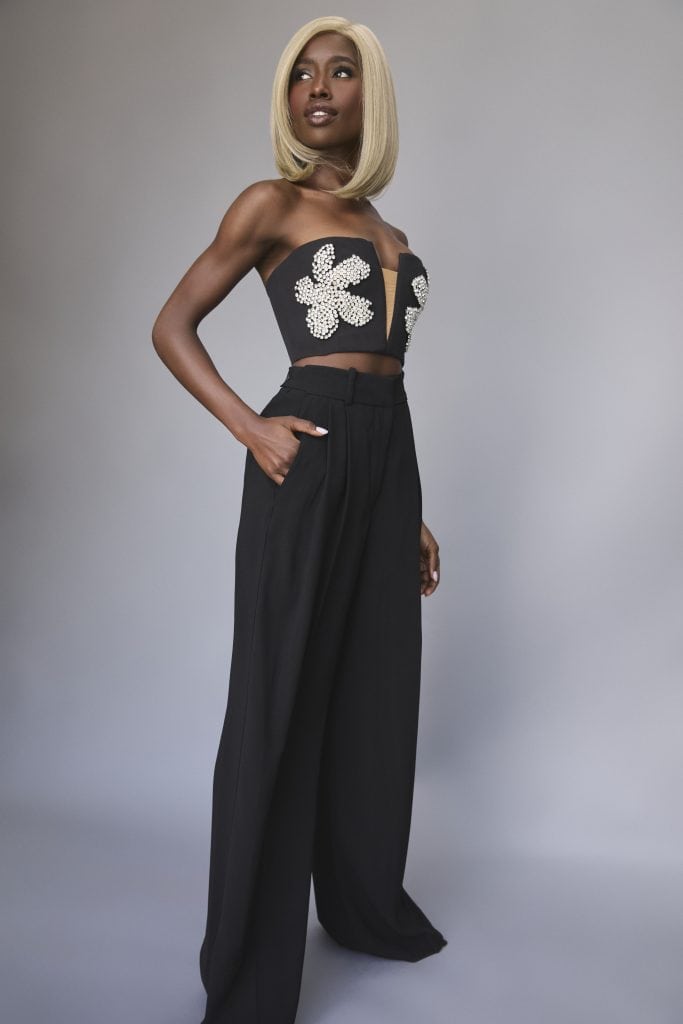 Blonde bob wig styled on a woman with a strapless top and wide-leg pants.